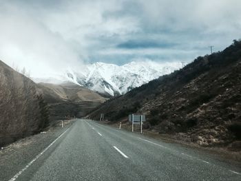 Road amidst snowcapped mountains against sky