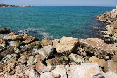 Rocks by sea against blue sky