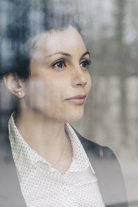 Close-up of thoughtful businesswoman seen through glass window at office