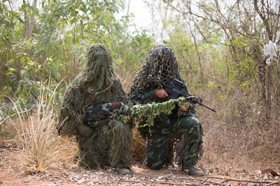 Army soldiers with rifle kneeling in forest