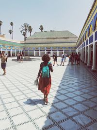 People on tiled floor in building against clear sky