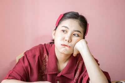 Thoughtful young woman against pink background