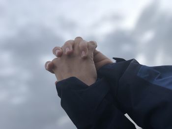 Close-up of man hand against sky