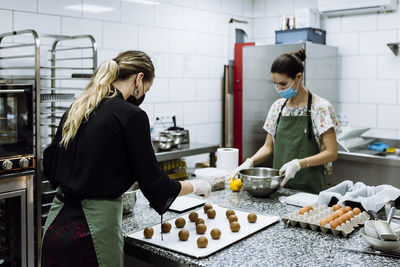 Young woman standing by people in kitchen