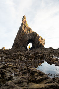 Person on rock formation against sky