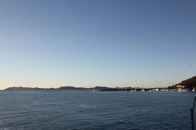 Scenic view of sea and mountains against clear blue sky