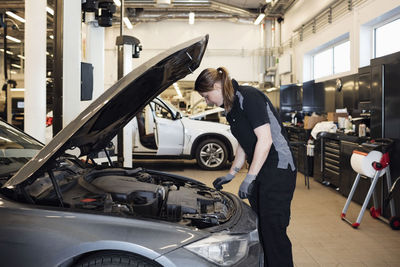 Side view of woman examining car in shop