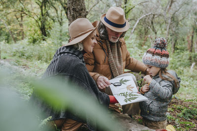 Grandparents and girl collecting leaves in forest