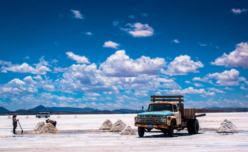 Truck on salt flat at salar de uyuni against sky