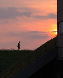 Silhouette man standing on field against sky during sunset