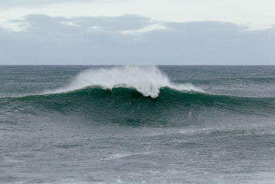 Waves splashing on sea against sky