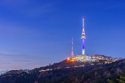 Communications tower in city against blue sky