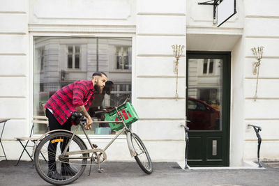 Owner locking bicycle on sidewalk outside candy store