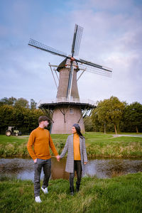 Couple holding hands while standing on land against sky