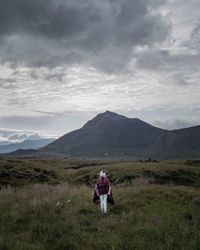 Rear view of men walking on mountain against sky