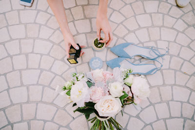 High angle view of woman holding rings in bottle by bouquet on footpath