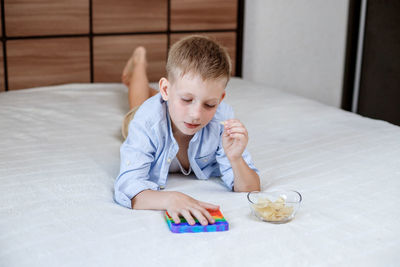 Full length of cute baby boy on bed at table