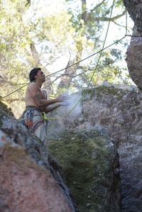 Low angle view of man sitting on rock