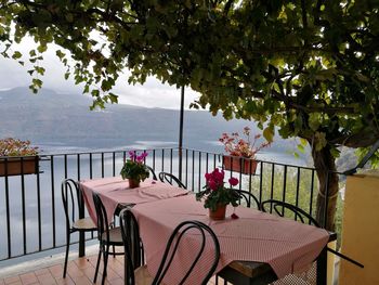 Chairs and table at restaurant by sea against sky