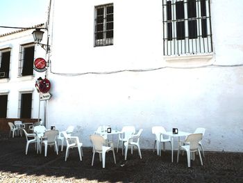 Empty chairs and tables against wall in city