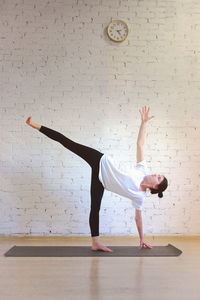 Woman doing yoga on floor against wall