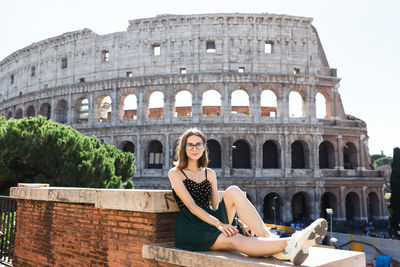Woman sitting on historical building