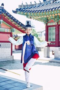 Portrait of smiling woman in traditional clothes standing against building 