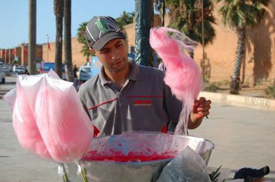 Portrait of young man holding pink while sitting outdoors