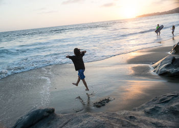 Full length of man on beach against sky during sunset