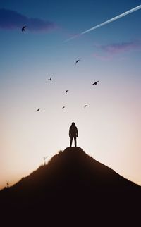 Low angle view of silhouette man standing on mountain against sky