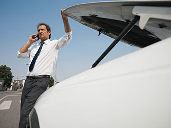 Low angle view of man using mobile phone against sky