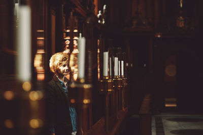 Thoughtful young woman standing by candles in church