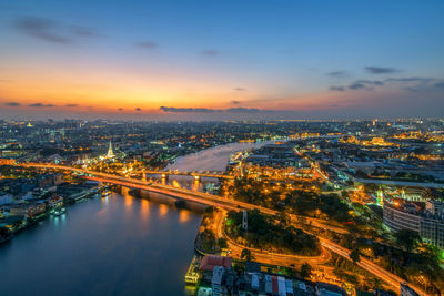 High angle view of illuminated bridge and buildings against sky during sunset