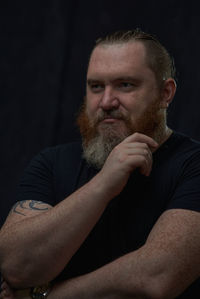 Portrait of senior man looking away against black background