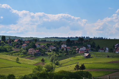 Scenic view of green landscape and houses against sky
