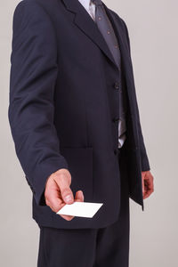 Midsection of businessman holding paper against white background