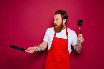 Young man holding food against red background