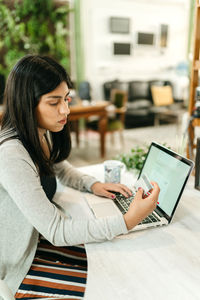 Side view female making purchase with plastic card for order during online shopping via laptop