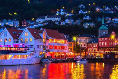 Illuminated buildings by river at night