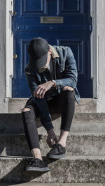 Man adjusting shoe on steps against door