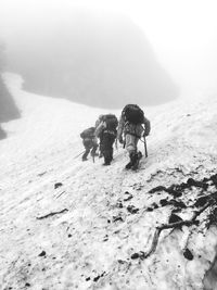 Rear view of people mountain climbing during winter