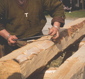 Midsection of carpenter cutting wood