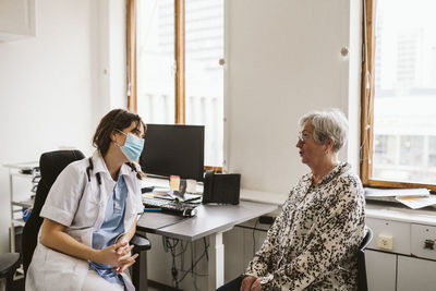 Female doctor consulting senior patient during covid-19