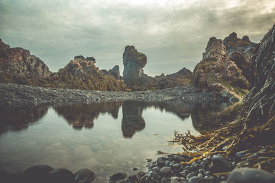 Reflection of rocks in lake against sky