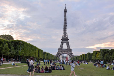 Crowd in park by eiffel tower against sky