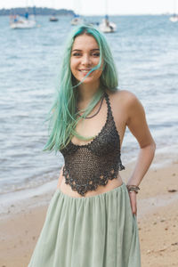 Portrait of smiling young woman standing on beach