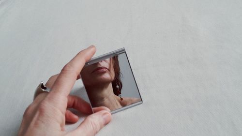 Cropped hand of woman holding mirror over table