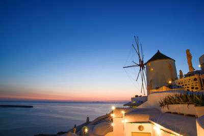 Traditional windmill at santorini against blue sky during sunset