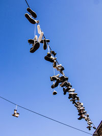 Low angle view of flags hanging against clear blue sky