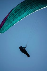 Low angle view of person paragliding against clear sky